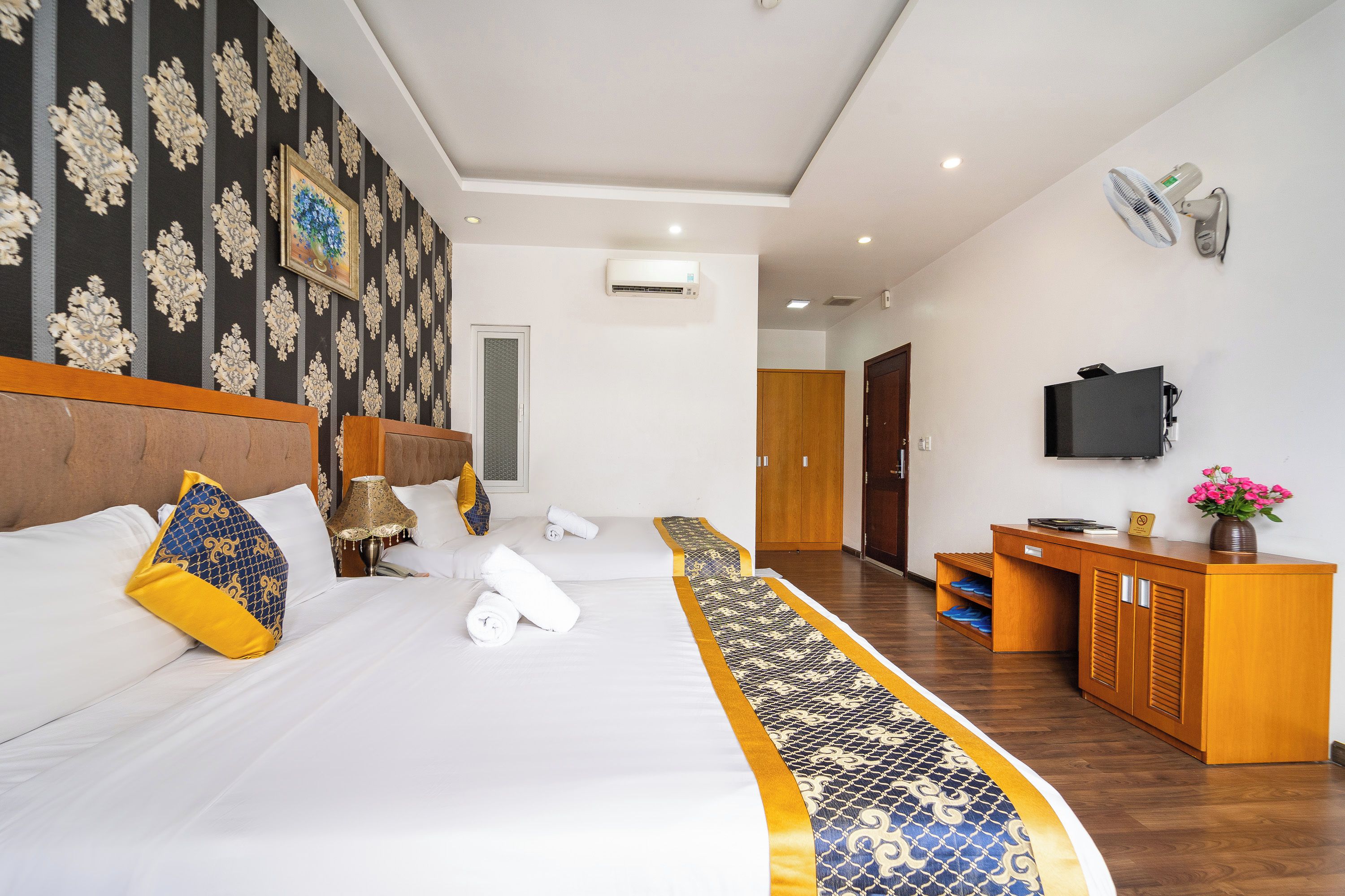 A hotel room with a large bed, a desk, a television, and a wardrobe.