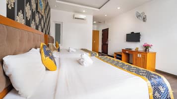 Una habitación de hotel con cama, escritorio, televisión y aire acondicionado.