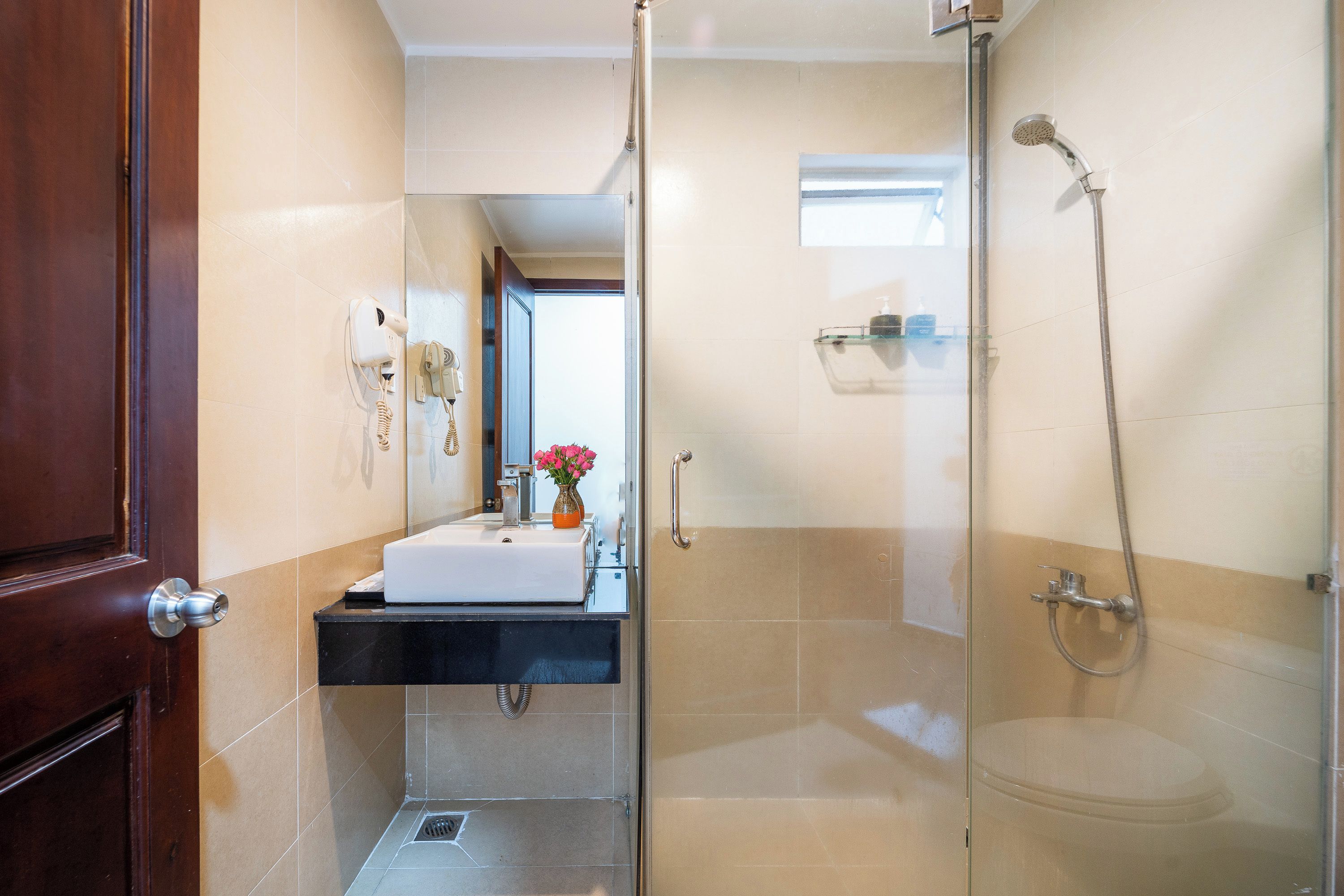 A bathroom with a glass shower enclosure, a sink with a mirror, and a door.