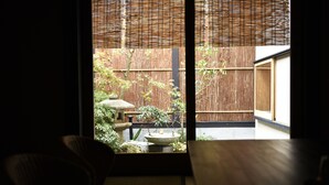 A view through a window of a traditional Japanese room with tatami flooring, a low wooden table, and a bamboo screen. - Kuraya Kamigojo-cho (Kyoto)