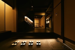 A dimly lit hallway with a staircase leading to a room with a traditional sliding door.
