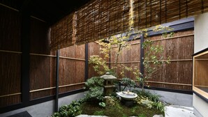 A traditional Japanese garden with a stone lantern, moss, rocks, and a bamboo fence. - Kuraya Kamigojo-cho (Kyoto)