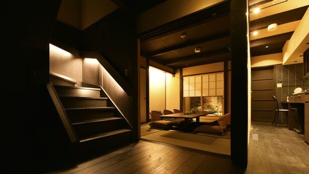 A modern interior with a wooden staircase leading to a dining area with a low table and chairs. - Kuraya Kamigojo-cho (Kyoto)