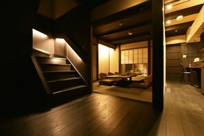 A modern interior with a wooden staircase leading to a dining area with a low table and chairs. - Kuraya Kamigojo-cho (Kyoto)