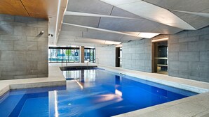 An indoor swimming pool with a clear view of the pool area, tiled walls, and a modern ceiling design.