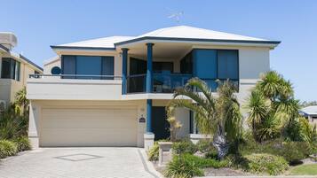 A two-story house with a garage, a balcony, and a well-maintained garden.