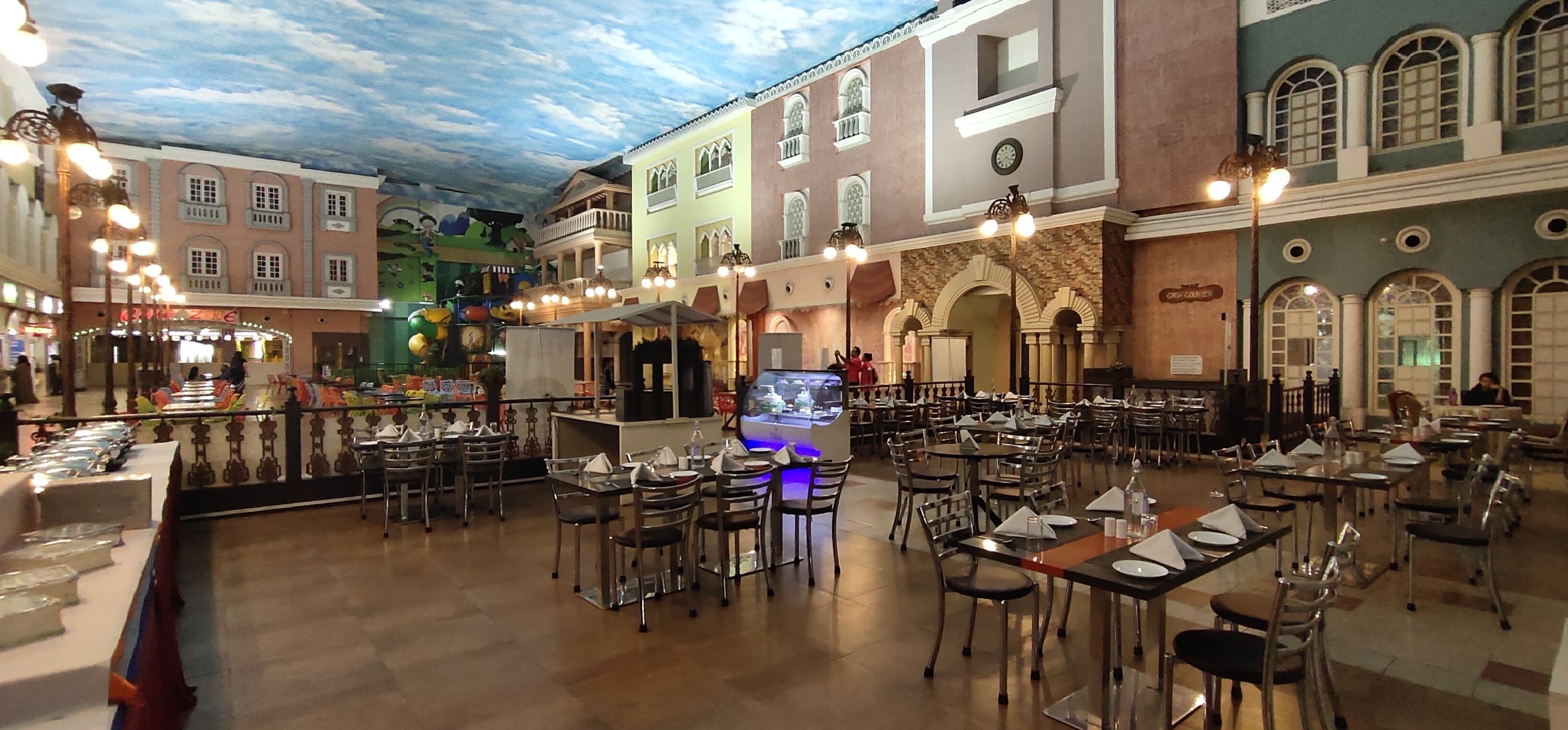 Un restaurant doté de plusieurs tables et chaises, d’un bar et d’une scène pour les spectacles.
