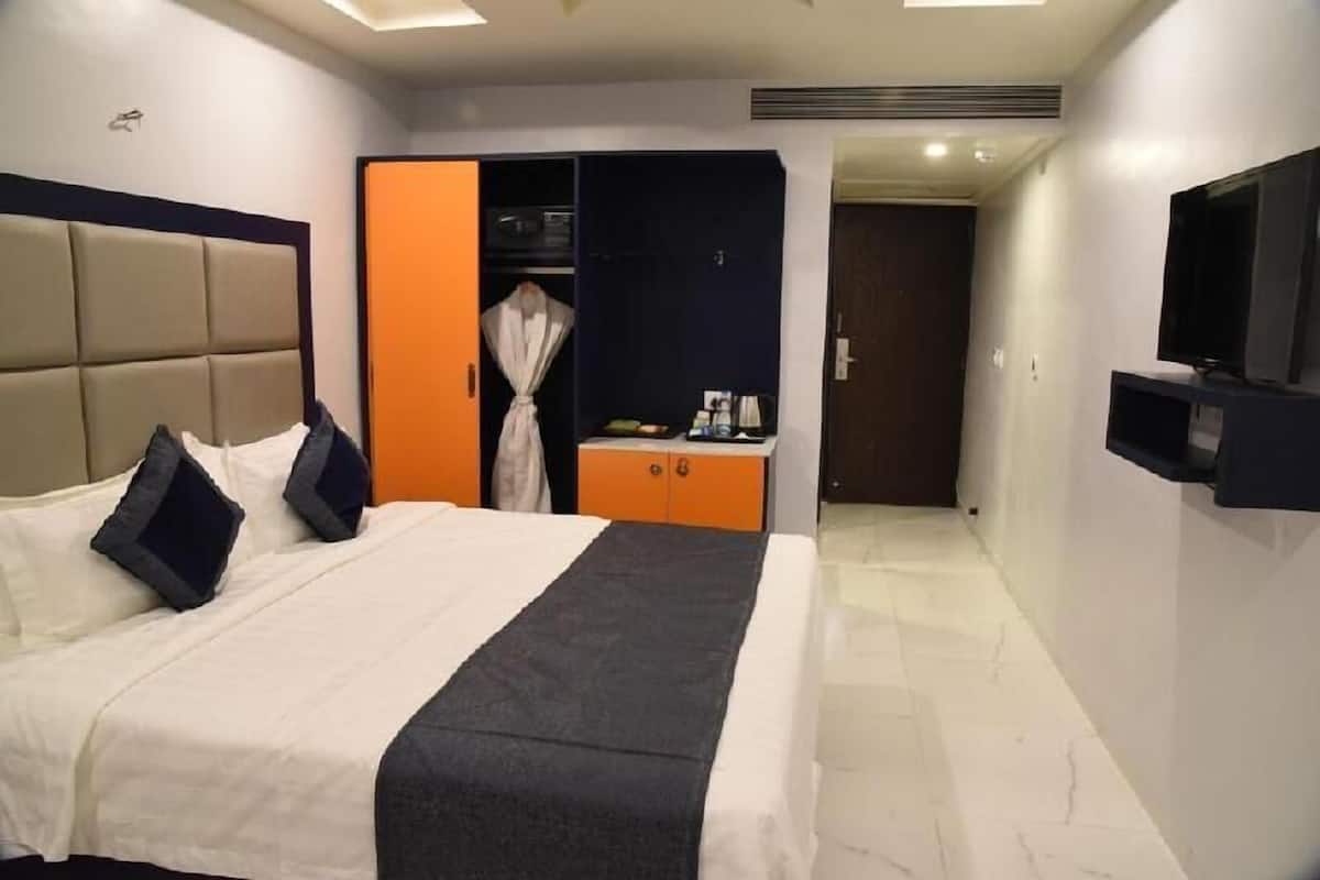 Una habitación de hotel con cama, armario, televisor y una mesita con bandeja.