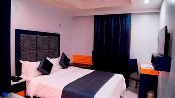 A hotel room with a bed, a desk, a chair, a television, and a ceiling fan.