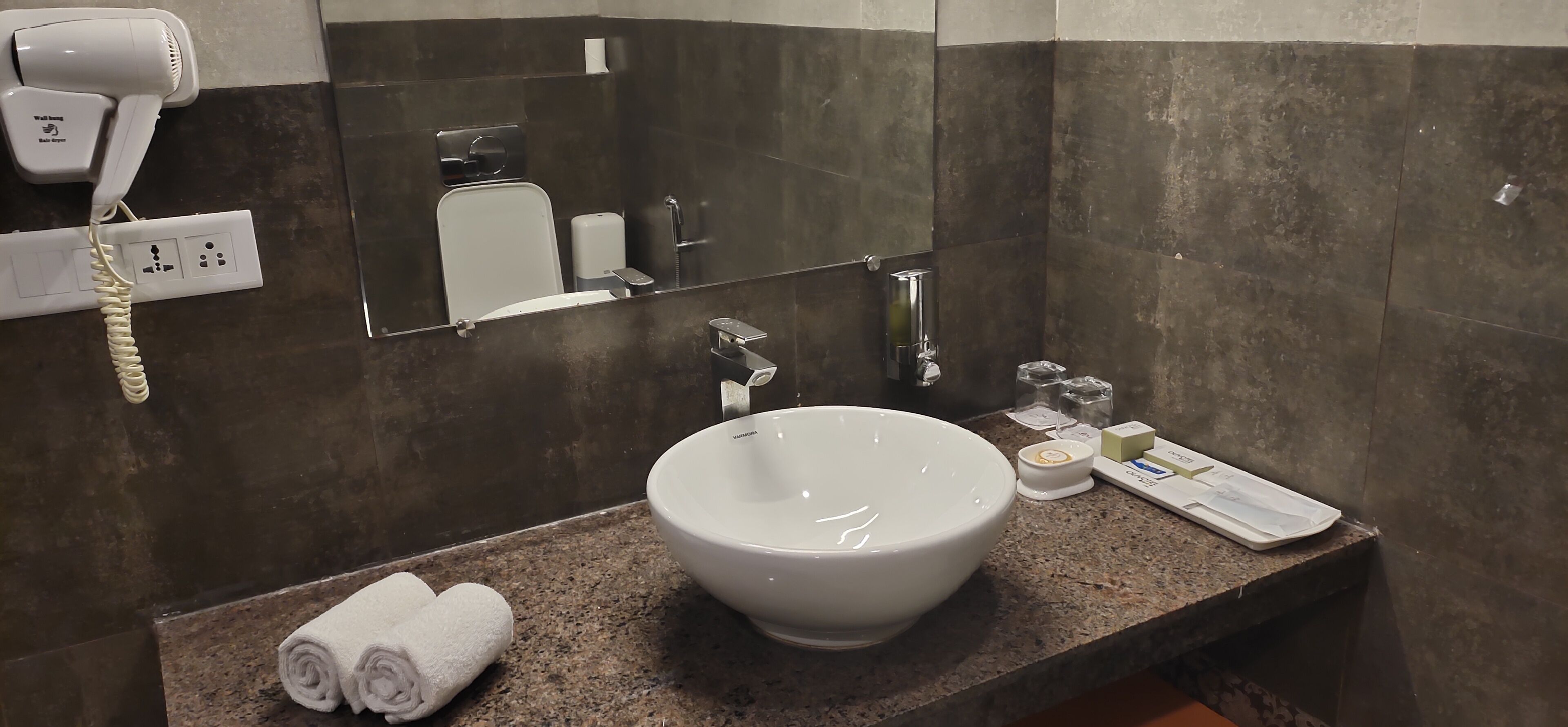 Un baño con lavamanos blanco, secador de pelo y espejo.