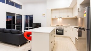 Eine moderne Küche mit weißen Schränken, einem eingebauten Backofen und einem Edelstahl-Kühlschrank.