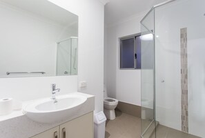 A modern bathroom with a glass shower enclosure, a white sink, and a toilet.