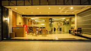 A hotel lobby with a reception desk, seating area, and a staircase leading to upper floors. - Raja Residence (Jakarta)