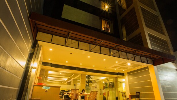 A brightly lit hotel entrance with a glass facade, outdoor seating area, and a visible reception desk. - Raja Residence (Jakarta)