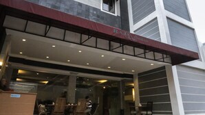 A modern hotel with a prominent entrance, a covered outdoor seating area, and a large glass facade. - Raja Residence (Jakarta)