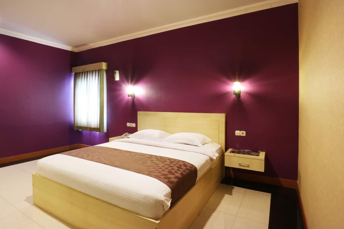 A hotel room with a bed, a nightstand, and two wall-mounted lights.