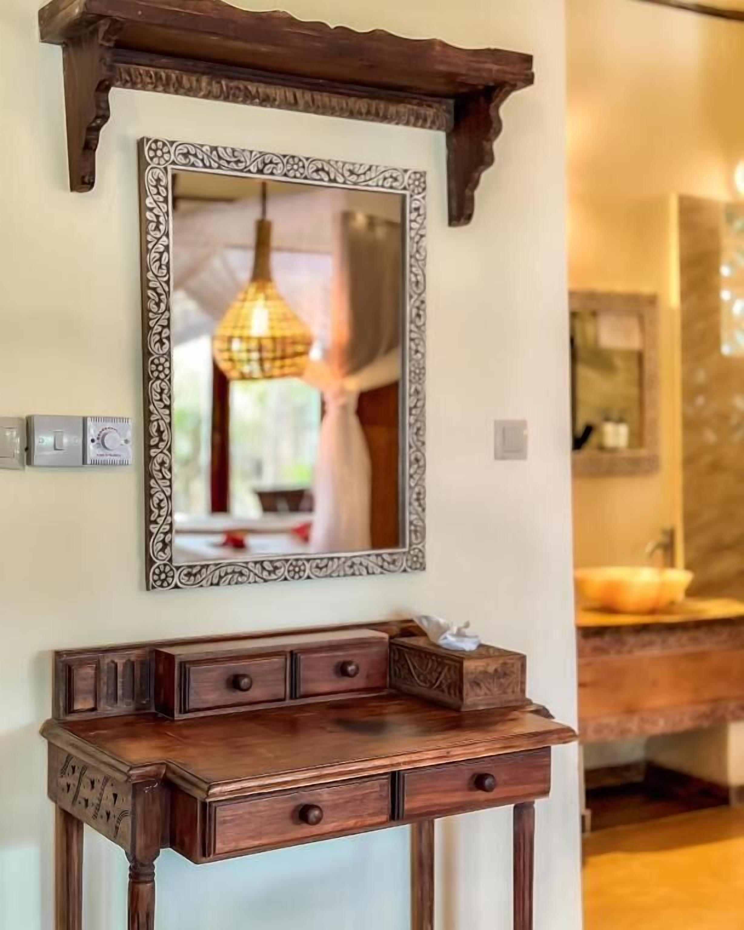 A wooden console table with drawers and a mirror above it.