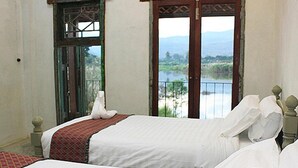 Un dormitorio con dos camas, vistas a un lago y un balcón con barandilla.