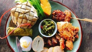 Un plato de comida con carne a la parrilla, verduras y un alimento envuelto.