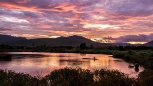 Una puesta de sol serena sobre un lago tranquilo, con montañas al fondo.