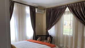 A hotel room with a bed, curtains, a chair, and a window. - Villa Sofia Kota Bunga (Cipanas)
