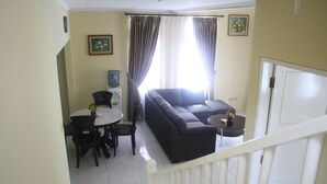 A living room with a sofa, a dining table with chairs, and a water dispenser. - Villa Sofia Kota Bunga (Cipanas)