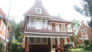 A two-story house with a balcony on the upper floor, a front porch, and a tiled roof. - Villa Sofia Kota Bunga (Cipanas)