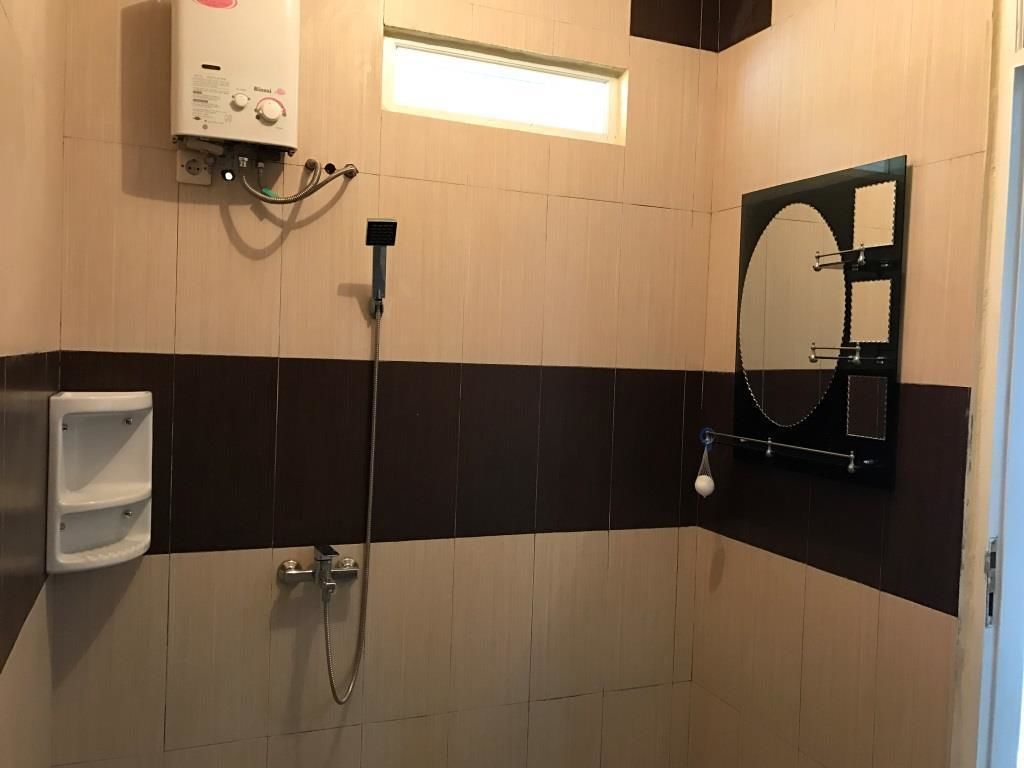 Un baño con ducha, inodoro, secador de manos y espejo.