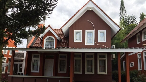 A two-story house with a sloped roof, a covered porch, and a brick pathway leading to the entrance. - Villa Sofia Kota Bunga (Cipanas)