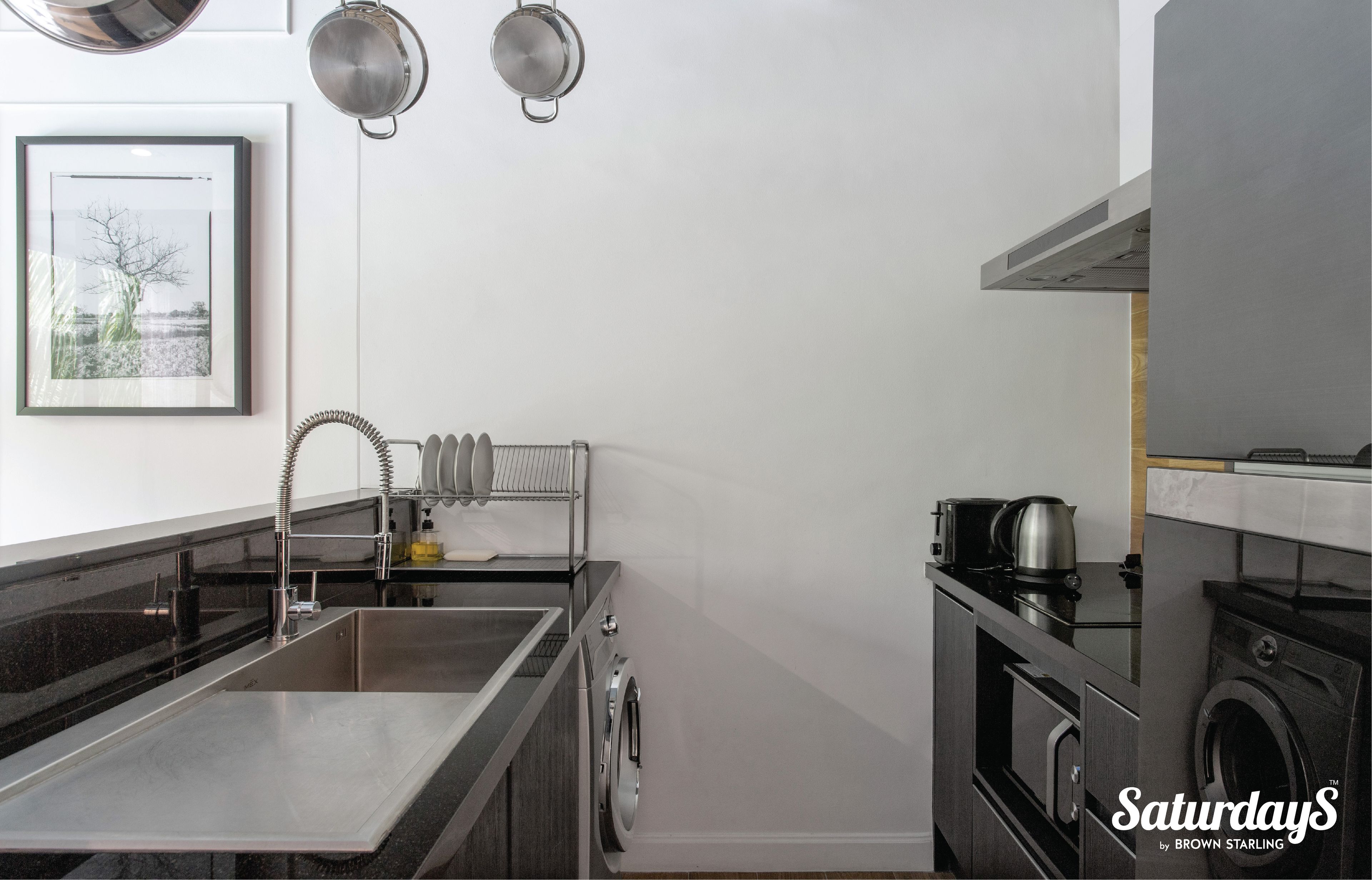 Una cucina moderna con lavello in acciaio inossidabile, bollitore e lavatrice.