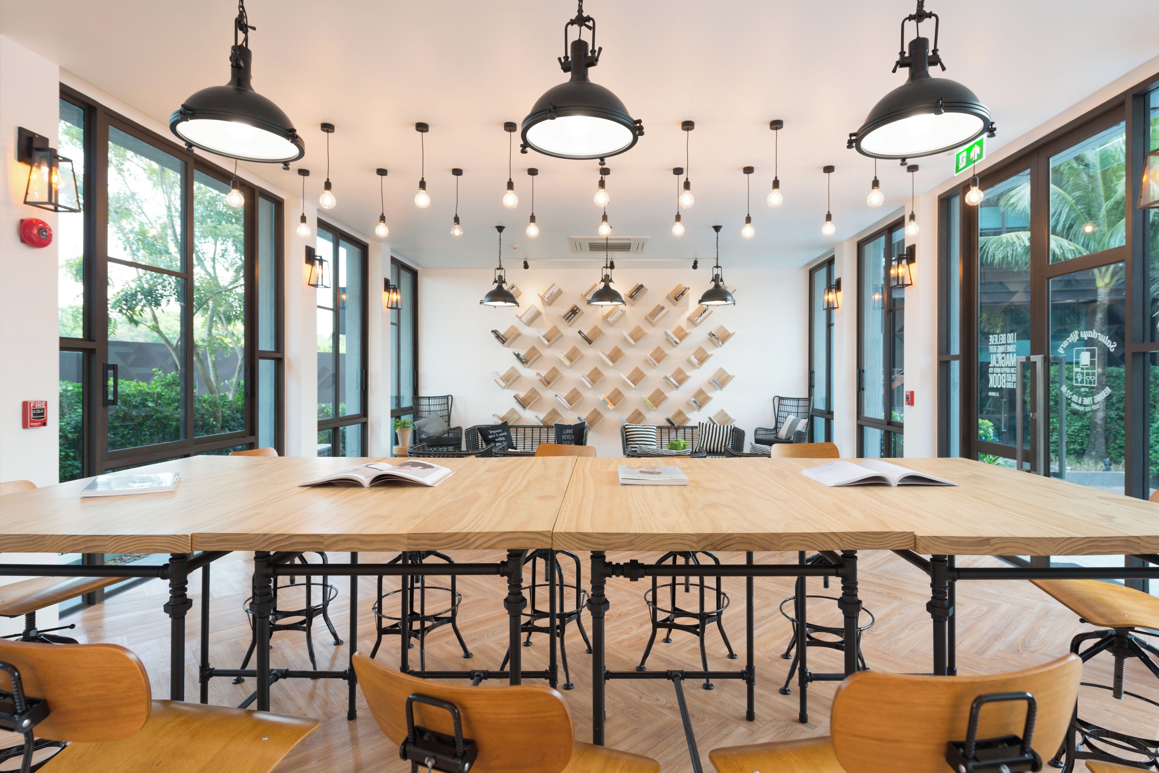 Un salón de conferencias con una amplia mesa, varias sillas, iluminación colgante y ventanas grandes que dan a zonas verdes.
