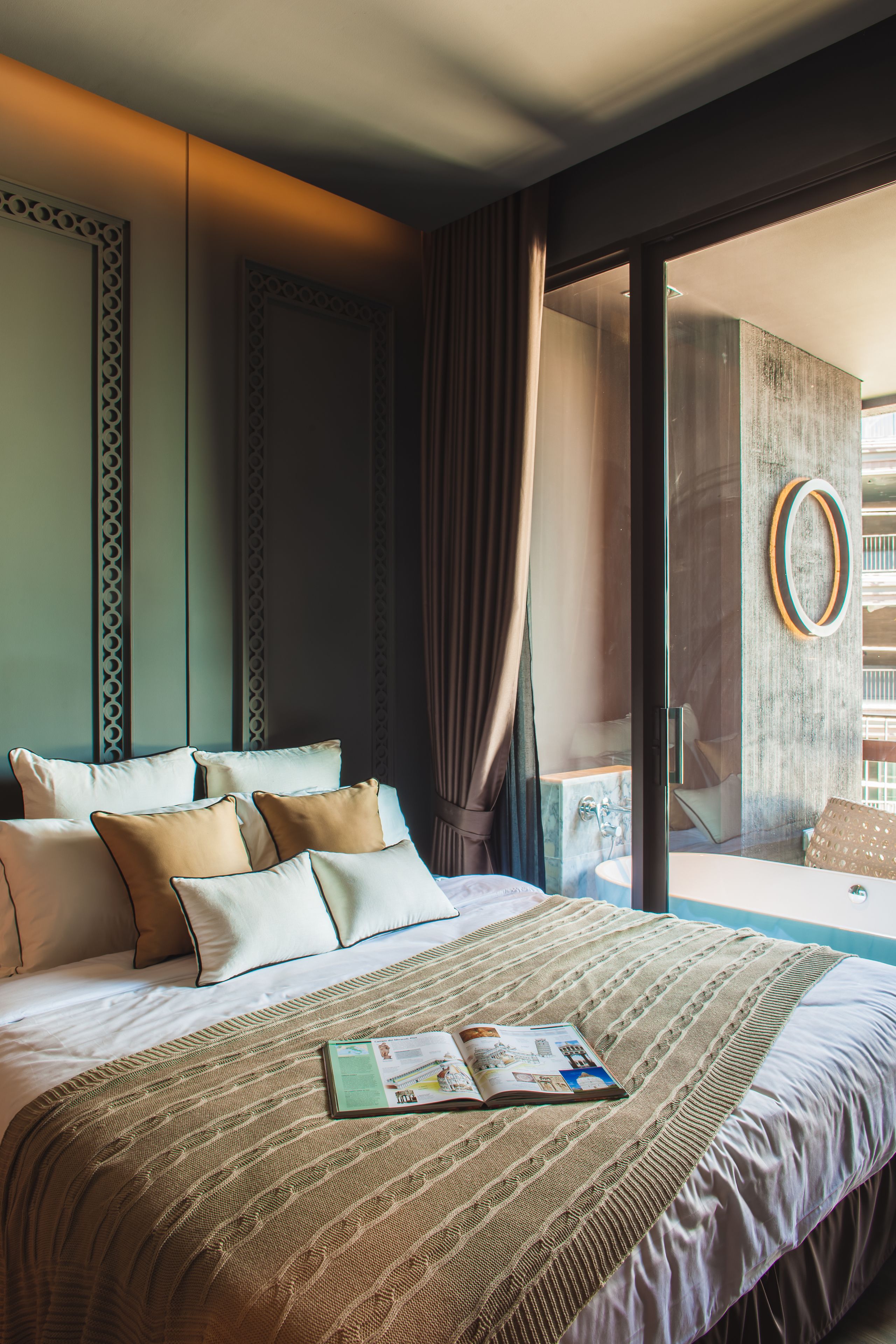 A hotel room with a large bed, a glass door leading to a balcony, and a view of the outside.