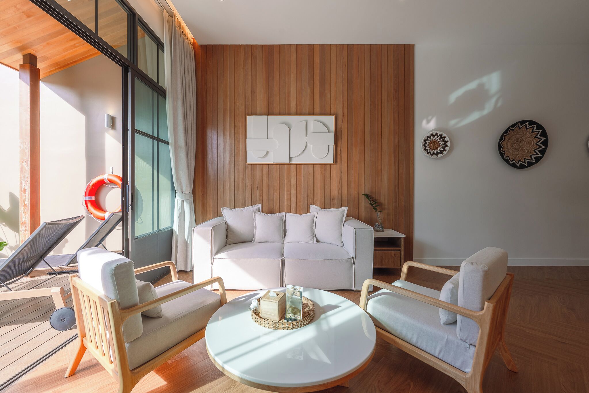 A modern living room with a white sofa, two armchairs, a coffee table, and a wooden accent wall.