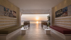 Un espace extérieur abrité, aménagé avec des sièges, d’où l’on peut admirer le coucher de soleil sur l’eau.