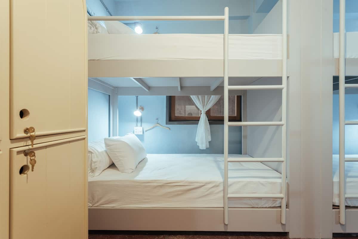 A bunk bed room with a wardrobe and a window with curtains.
