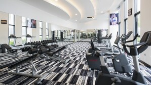 Un gimnasio con diferentes máquinas de ejercicio, ventanas amplias y un suelo con diseño.