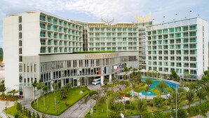 Un hotel moderno con una fachada ondulada distintiva, un patio central con piscina y una bandera en la entrada.