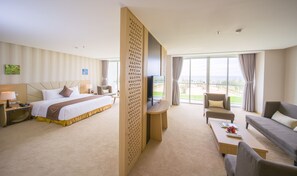 A hotel room with a bed, a TV, a sofa, and a balcony with a view.