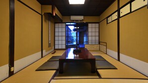 Perinteinen japanilainen huone, jossa on tatamimatto, matala pöytä ja liukuovet, joista on näkymä puutarhaan.