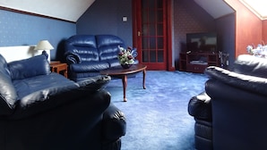 Una sala de estar con un sofá azul, un sillón azul, una mesa de centro de madera y un televisor.