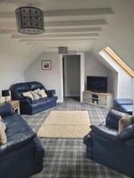 Un salón estilo loft con techo alto, un ventanal grande y un televisor de pantalla plana.