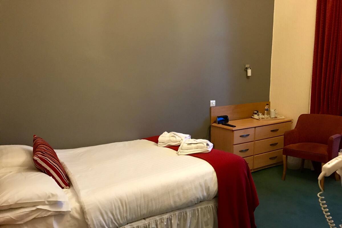 Ein Hotelzimmer mit Bett, Schminktisch, Stuhl und Telefon.