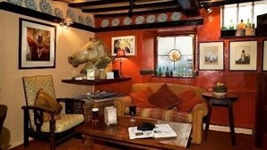 Une pièce chaleureuse avec une table basse en bois, un canapé, un fauteuil et une sculpture décorative représentant une tête de cheval.