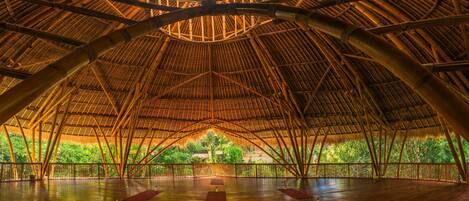 An indoor space with a high, arched bamboo ceiling and a wooden floor.