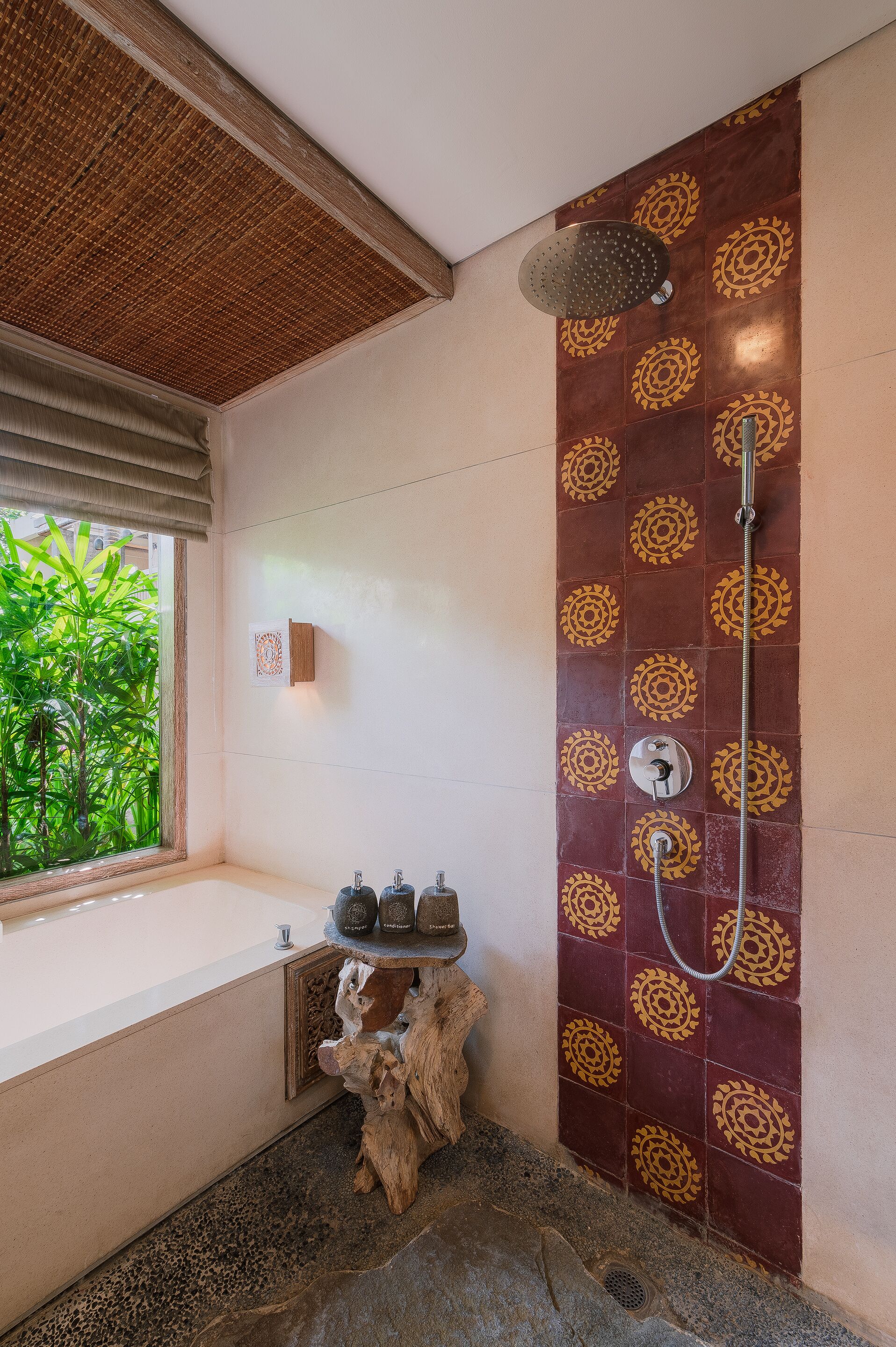 Un baño con ducha, ventana con vista a la vegetación y un detalle decorativo en la pared.