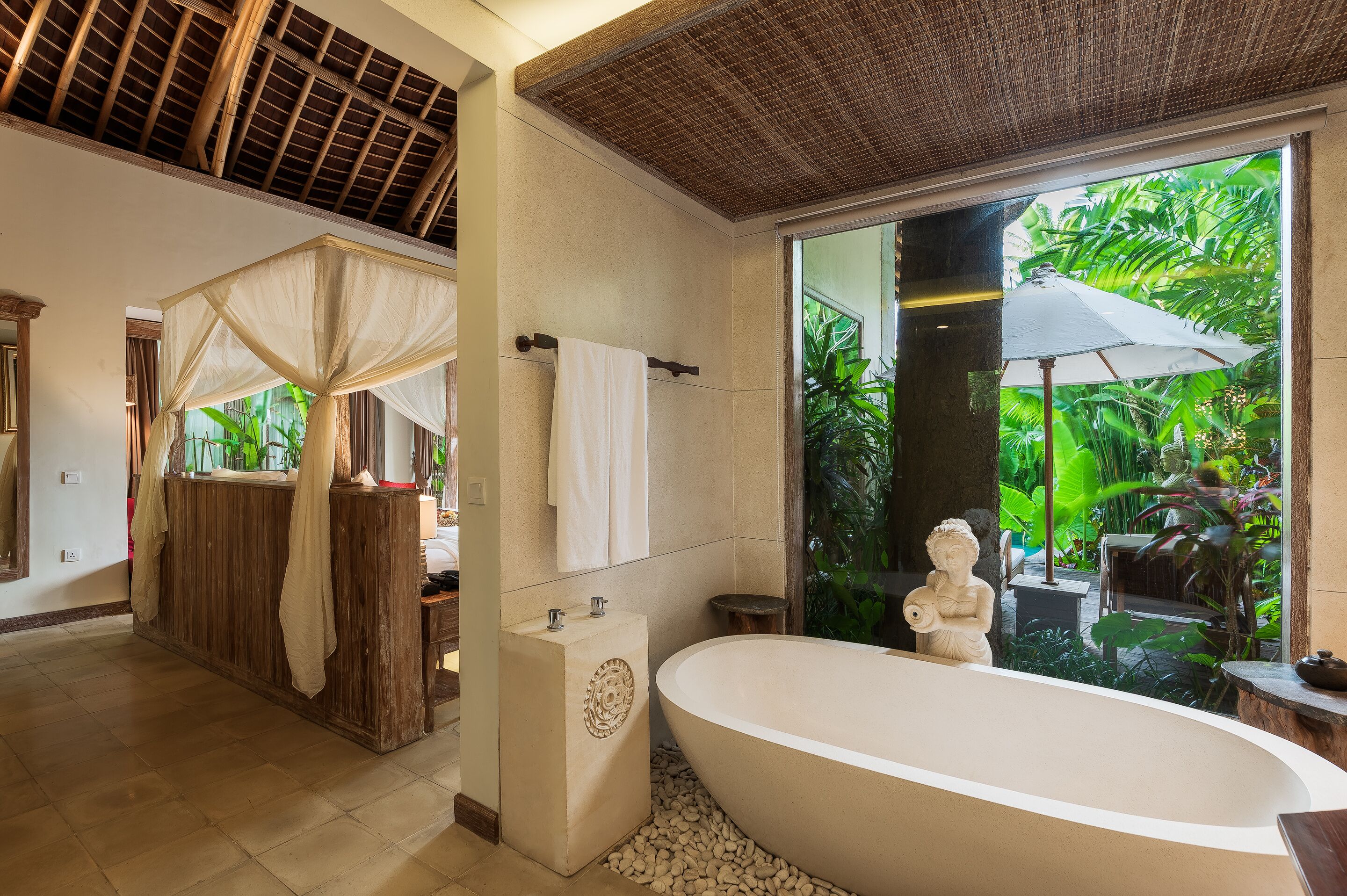 A bathroom with a large bathtub, a wooden vanity, and a shower area with a canopy.