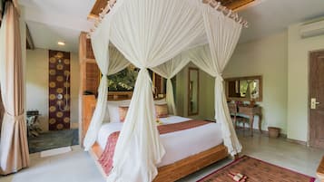 A spacious bedroom with a large bed, a wooden headboard, a canopy, and a bathroom with a shower and a mirror.
