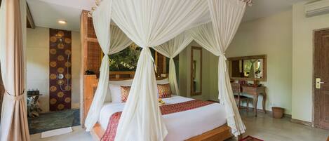 A spacious bedroom with a large bed, a wooden headboard, a canopy, and a bathroom with a shower and a mirror.
