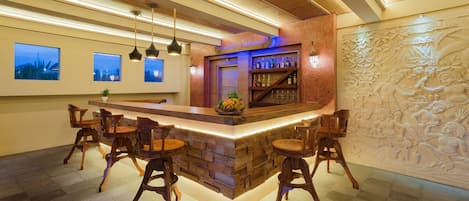 A bar area with a stone counter, wooden chairs, and a decorative wall.