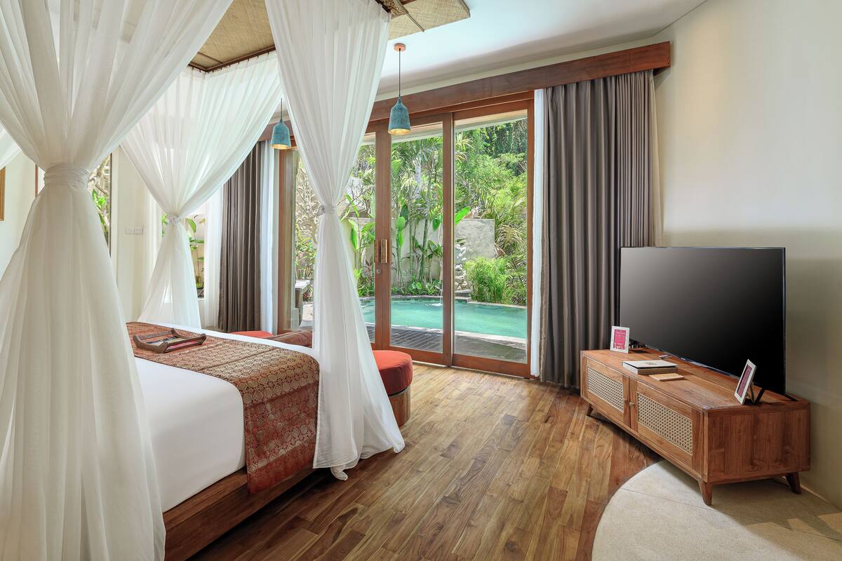 Un dormitorio con cama, televisión y vistas a una piscina.
